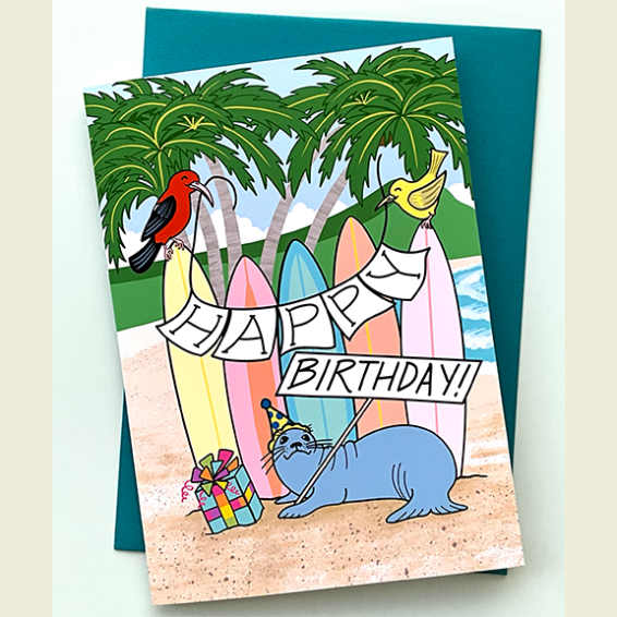 Birthday card with a seal, birds, and surfboards on a beach background
