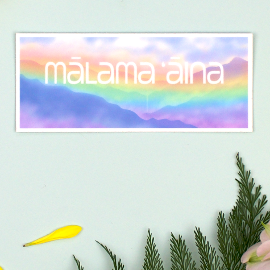 Sticker with a pastel rainbow illustration of the Hawaiian mountains and fog, with a distant waterfall in the center and the words, "Malama Aina"